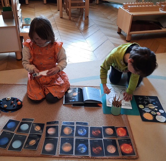 Two children working on the floor to match the shapes and colours of the planets.