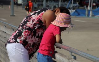 A mother and child having a conversation on a pier.