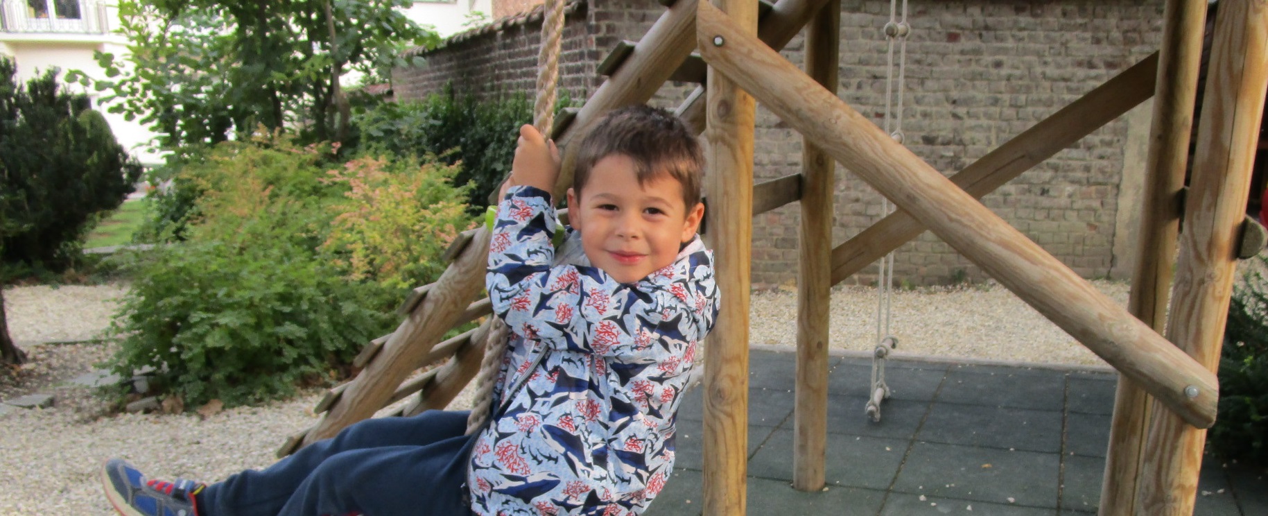 A child smiling at the camera while using the swing.