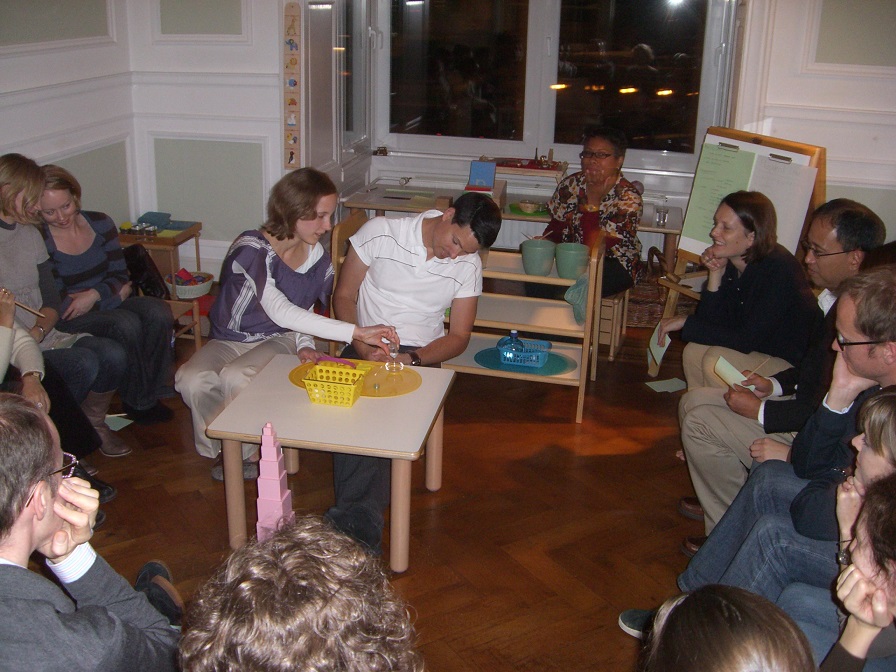 Parents are sitting in a classroom and learning about the materials the children are using in the classroom.