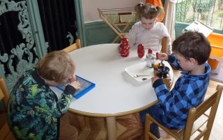 Three children are sitting at a table, each doing activities totally independently.